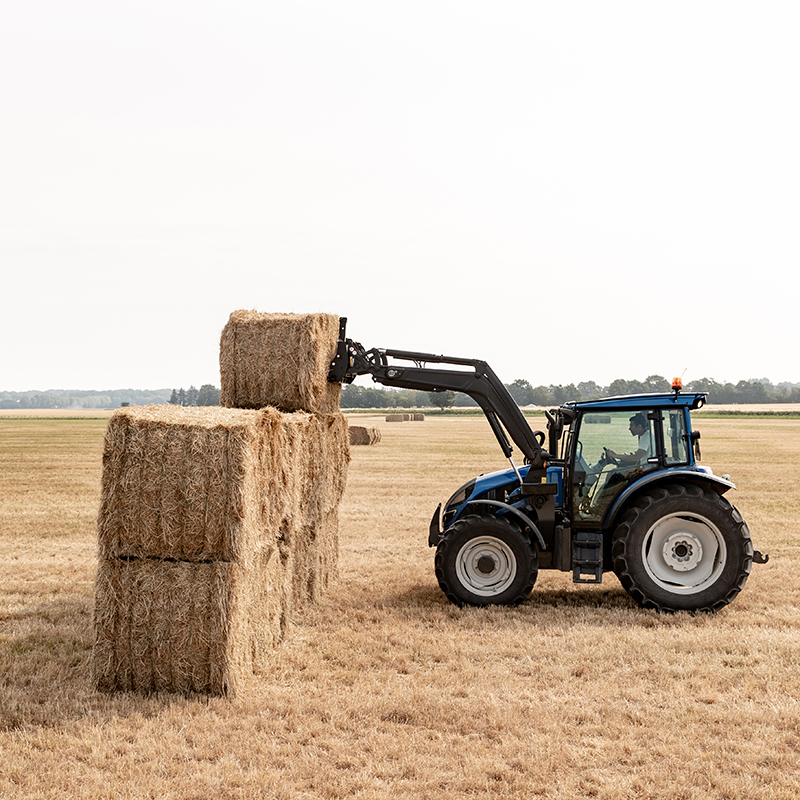 valtra a series tractor with frontloader lifting hay bales